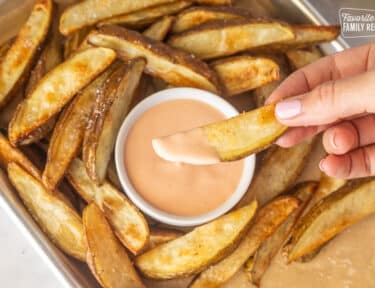 Hand holding a potato fry dipped in Fry Sauce.