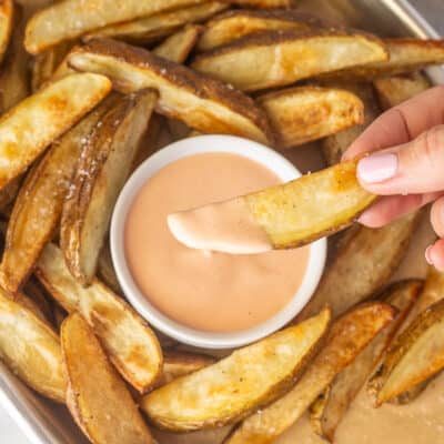 Hand holding a potato fry dipped in Fry Sauce.