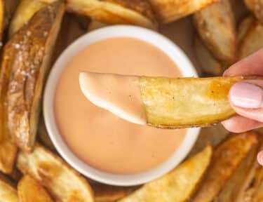 Hand holding a potato fry with Fry Sauce.