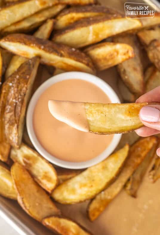 Hand holding a potato fry with Fry Sauce.