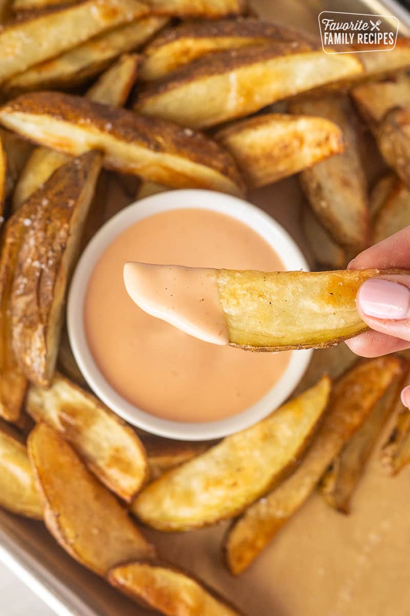 Hand holding a potato fry with Fry Sauce.