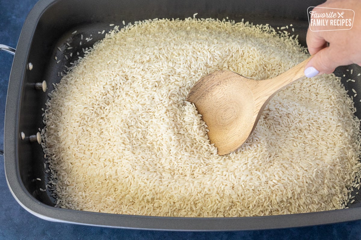 Spreading rice in a roasting pan with a wooden spoon.
