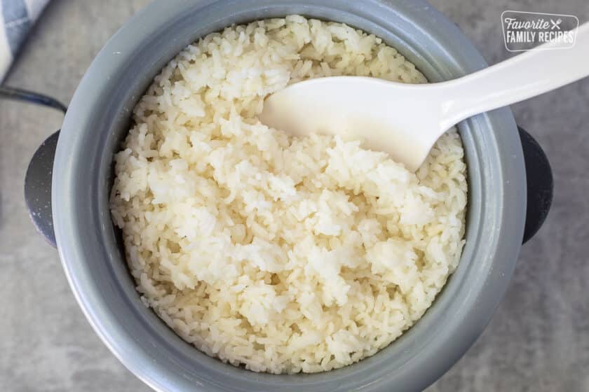 Rice cooker with rice and paddle inside.