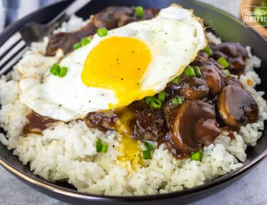 Close up of a bowl with Loco Moco topped with green onion.