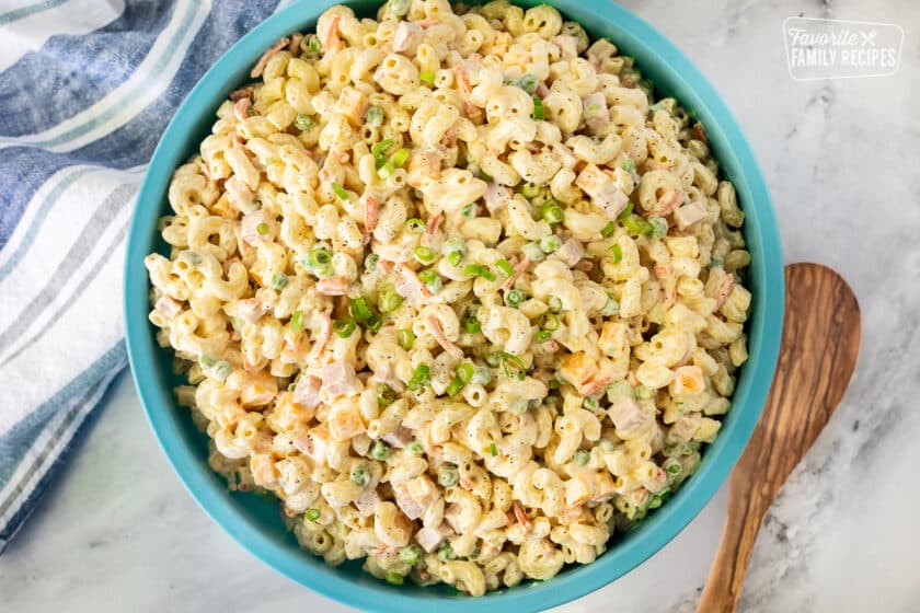 Large bowl of Macaroni Salad. Wooden spoon on the side.