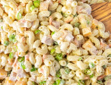 Bowl of Macaroni Salad with a wooden spoon.