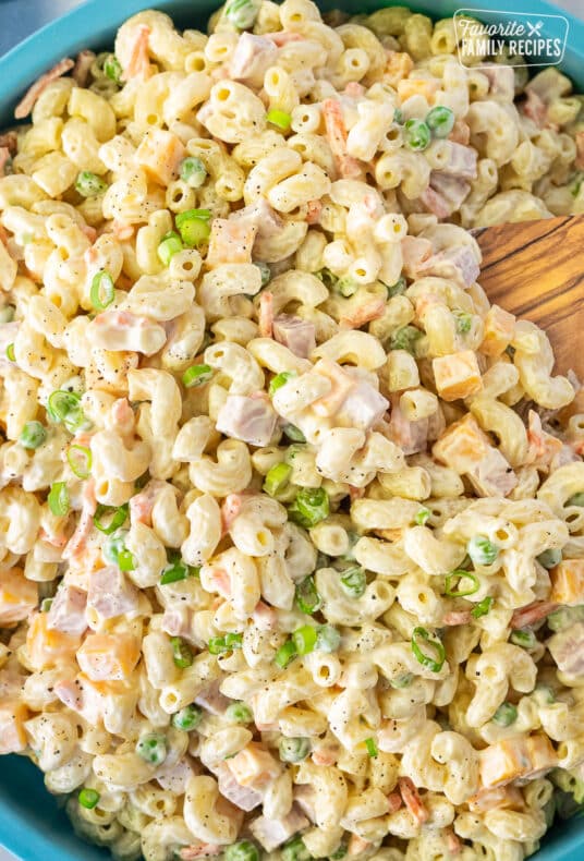 Bowl of Macaroni Salad with a wooden spoon.