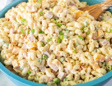 Large bowl of Macaroni Salad with wooden spoon.