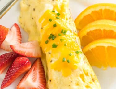 An omelette in a bag boiled in a pot on a plate with fresh fruit