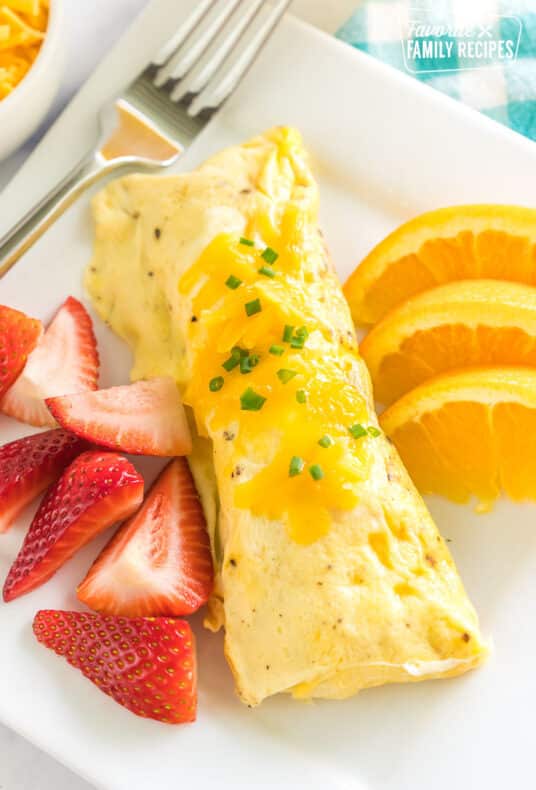 An omelette in a bag boiled in a pot on a plate with fresh fruit