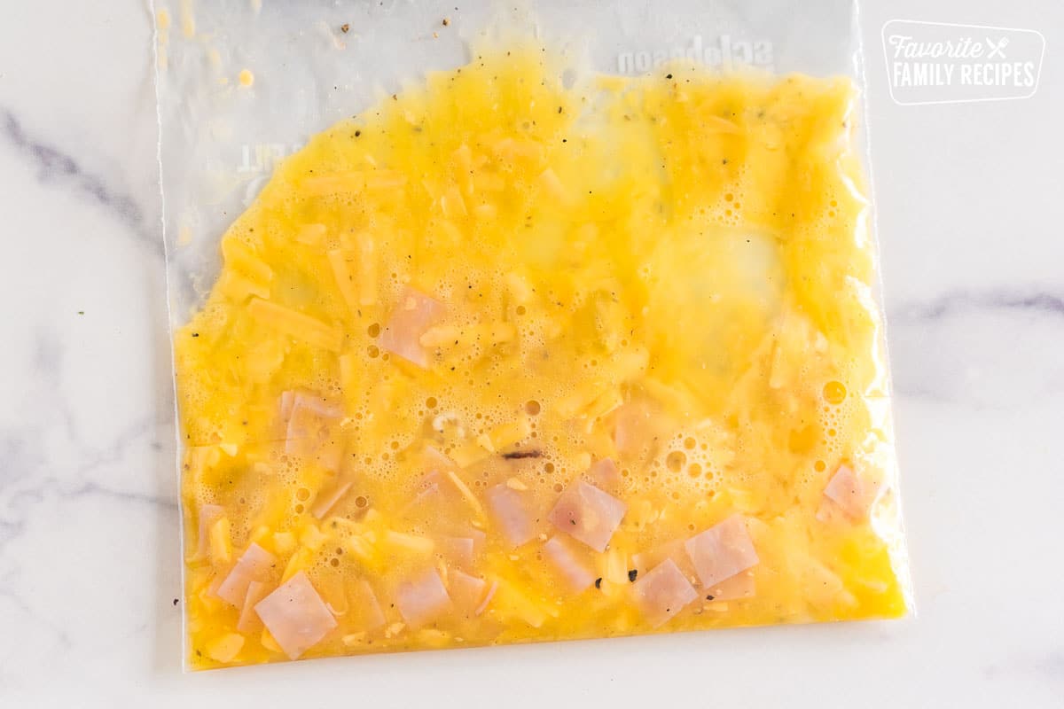eggs, ham, cheese and seasoning mixed in a ziplock bag