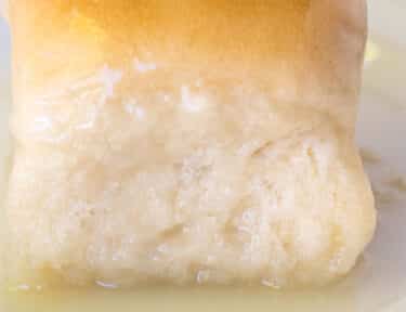 Close up of a Pani Popo Samoan Coconut roll on a plate with coconut sauce.