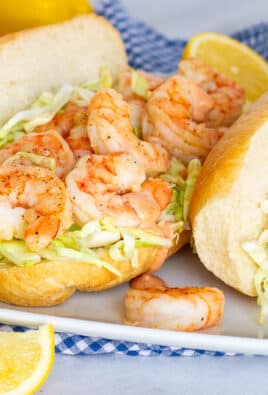 Shrimp Po'Boy Sandwiches with cabbage, sauce and lemon wedges.