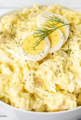 Bowl of Homemade Potato Salad with sliced hard boiled eggs on top and fresh dill.