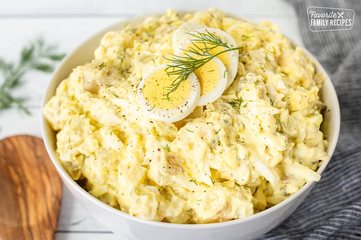 Bowl of Homemade Potato Salad with sliced hard boiled eggs on top and fresh dill.