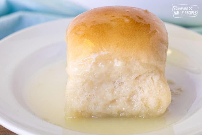 A sweet Pani Popo Samoan coconut roll on a plate basted in coconut sauce.