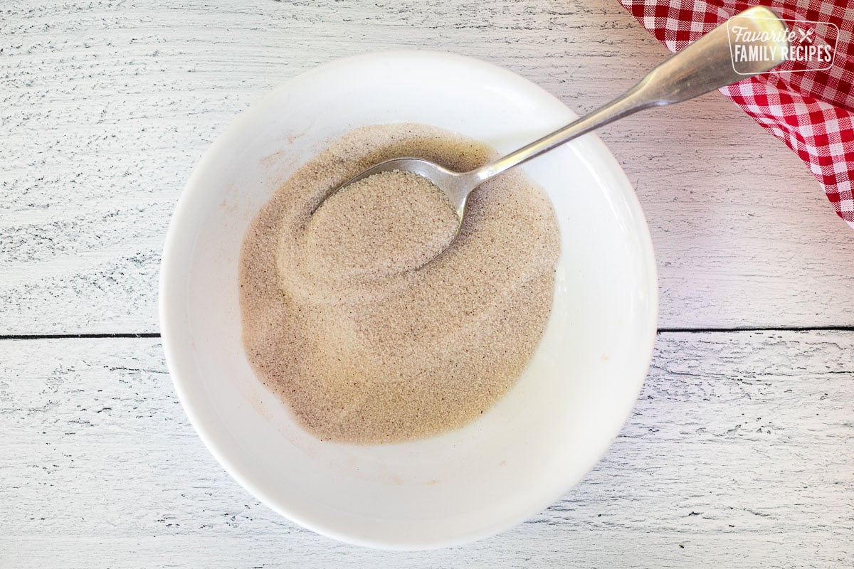 Bowl with mixed cinnamon and sugar with a spoon.