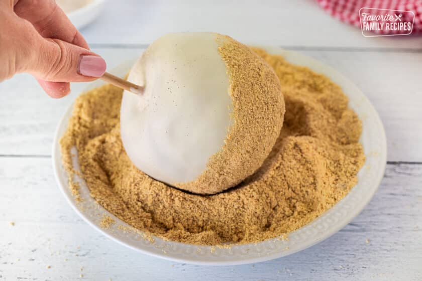 Rolling lower half of apple into crushed cinnamon graham crackers.