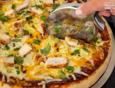 Cutting BBQ Chicken Pizza with a pizza slicer.