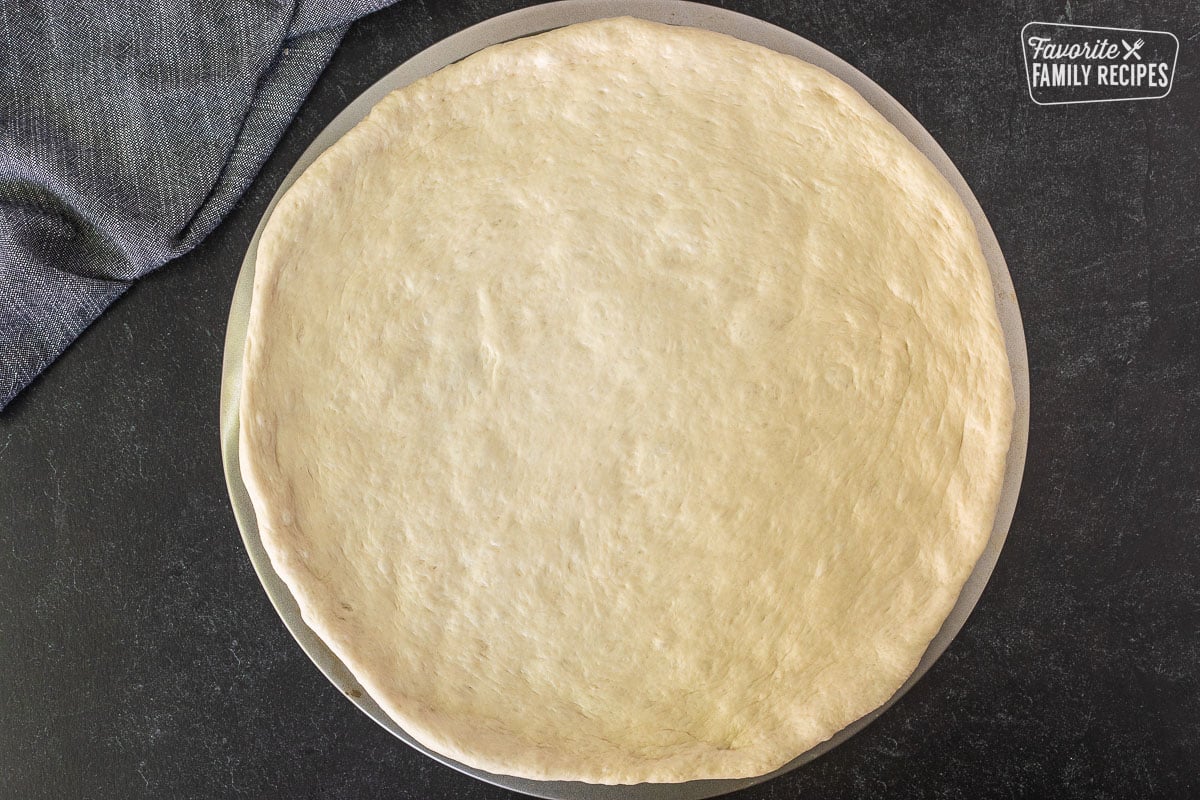 Rolled out pizza dough on a pan.