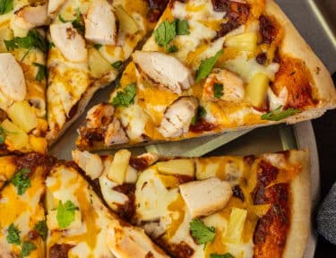 Slice of BBQ Chicken Pizza with chicken , cheese, and onions on a spatula.