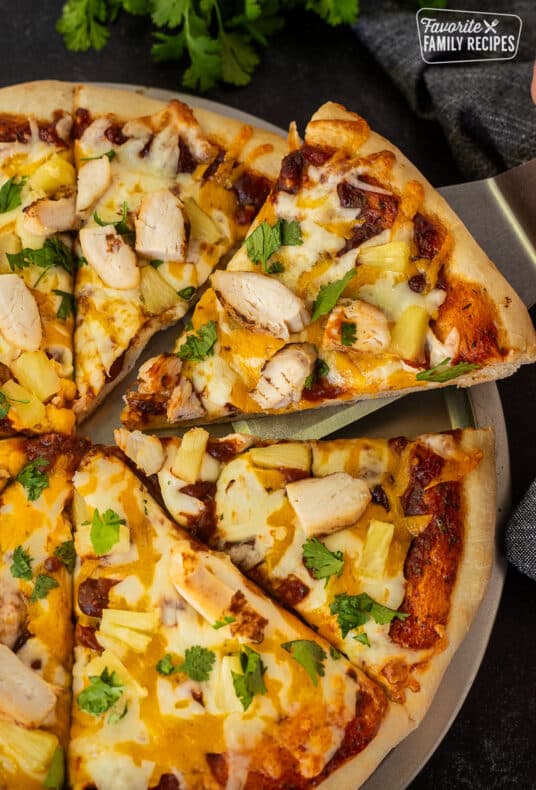 Slice of BBQ Chicken Pizza with chicken , cheese, and onions on a spatula.