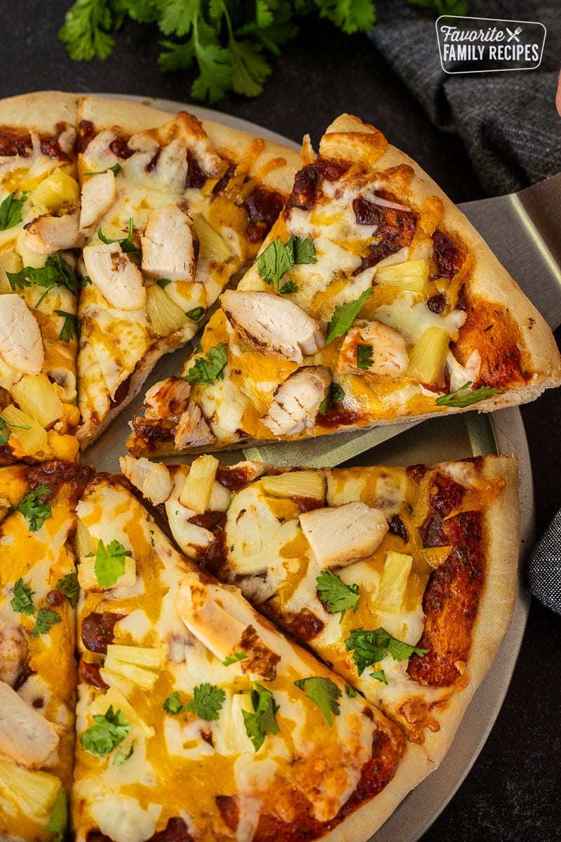 Slice of BBQ Chicken Pizza with chicken , cheese, and onions on a spatula.