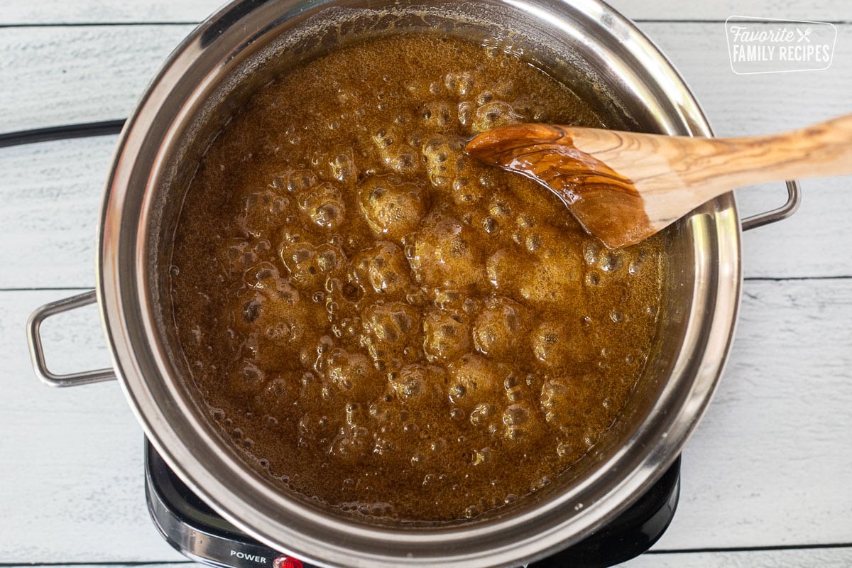 Boiling caramel in saucepan with wooden spoon.