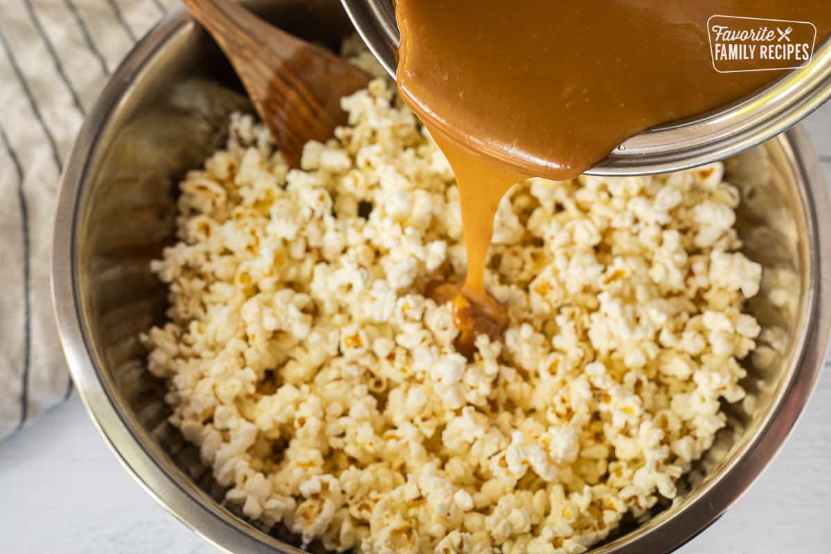 Pouring caramel on top of bowl of popcorn.