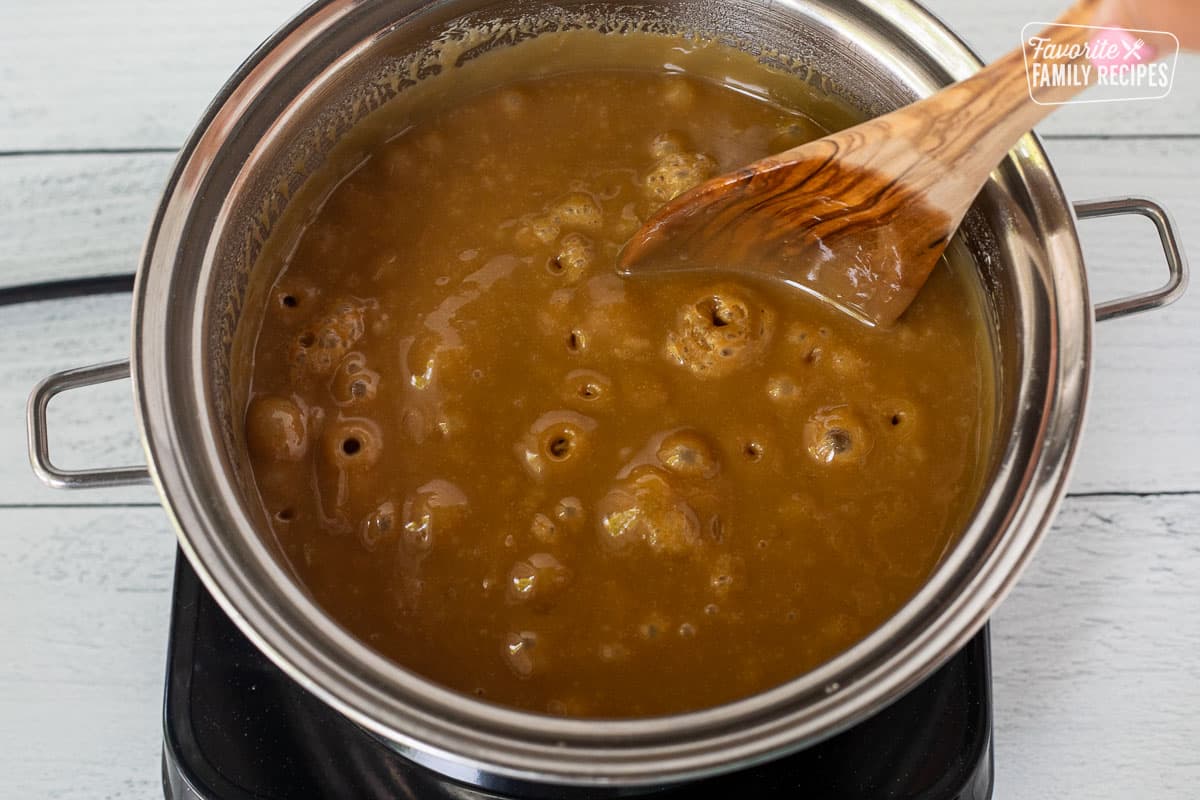 Boiling caramel in a saucepan with a wooden spoon.