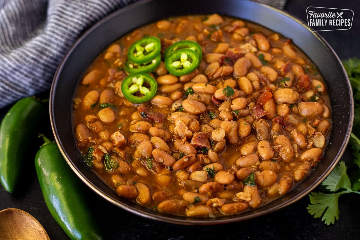 Charro Beans in a bowl garnished with sliced fresh jalapeños.