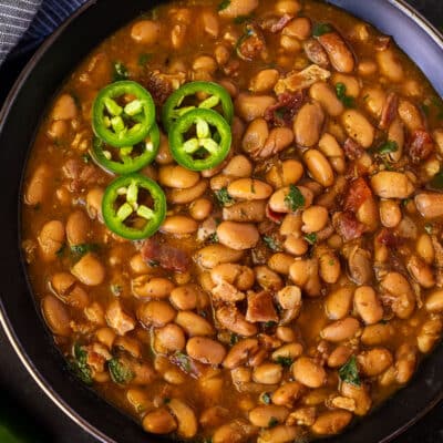 Bowl of Charro Beans garnished with sliced jalapeños.