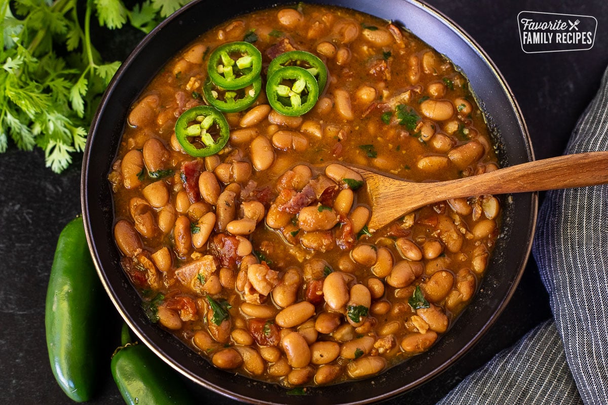 Large bowl of Charro Beans with a wooden spoon.