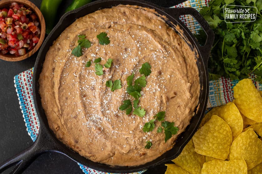 Skillet of Cheater Refried Beans with cojita cheese and cilantro. Tortilla chips and salsa on the side.