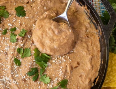 Spoon with Cheater Refried Beans in a skillet.