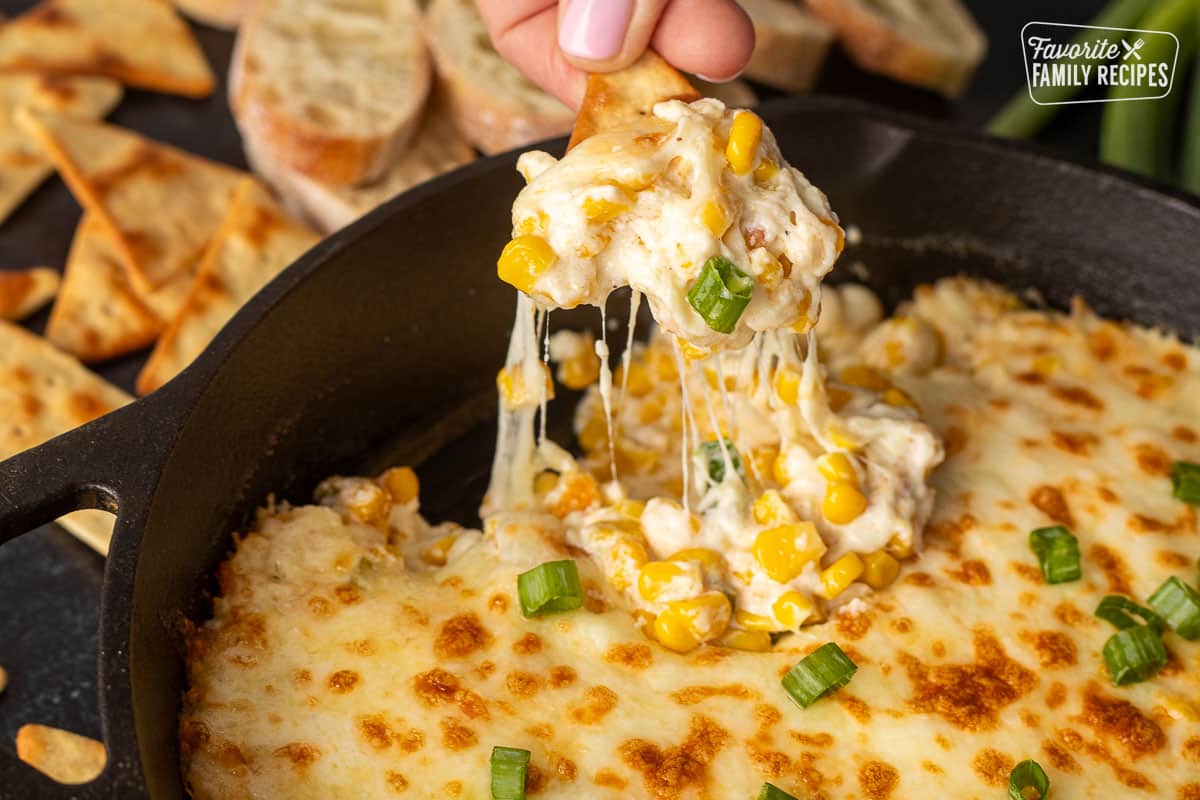 Corn Cheese on a cracker with the cheese pulling from the skillet.