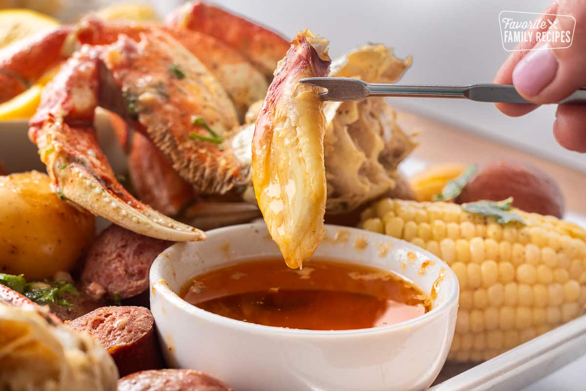 Dipping a piece of crab into a bowl of butter garlic.