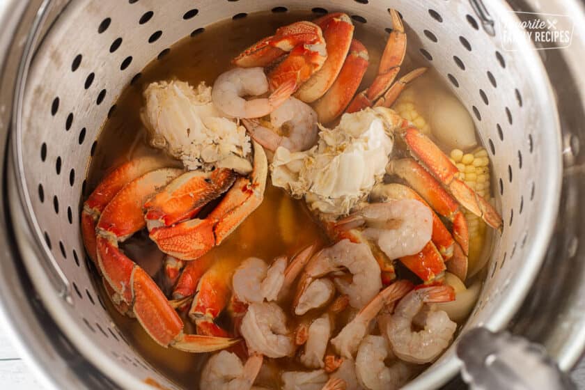 Stock Pot with crab legs and shrimp added to corn, onion and potatoes.