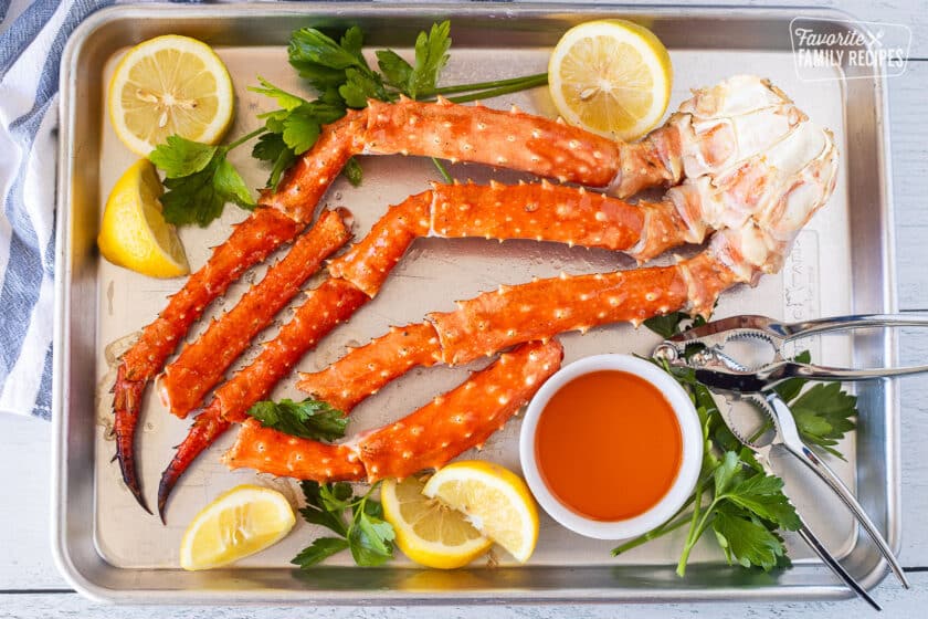 Sheet Pan with baked crab legs with lemon, parsley and butter.