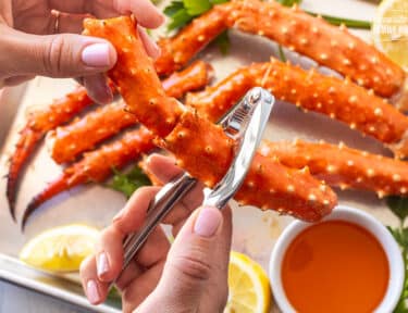 Cracking open a piece of king crab leg with a crab cracker tool.