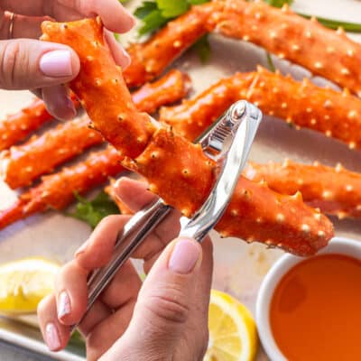 Cracking open a piece of king crab leg with a crab cracker tool.