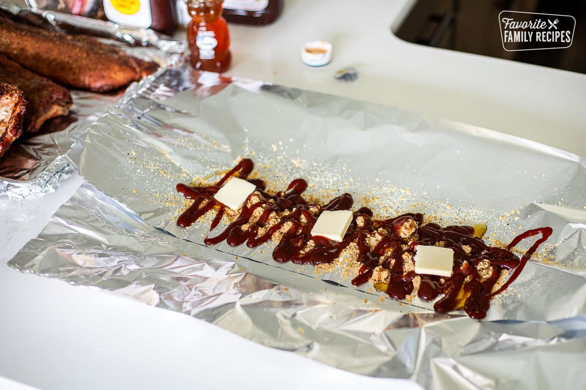 Foil with glaze ingredients including barbecue sauce, butter, Kinder's seasoning and honey.