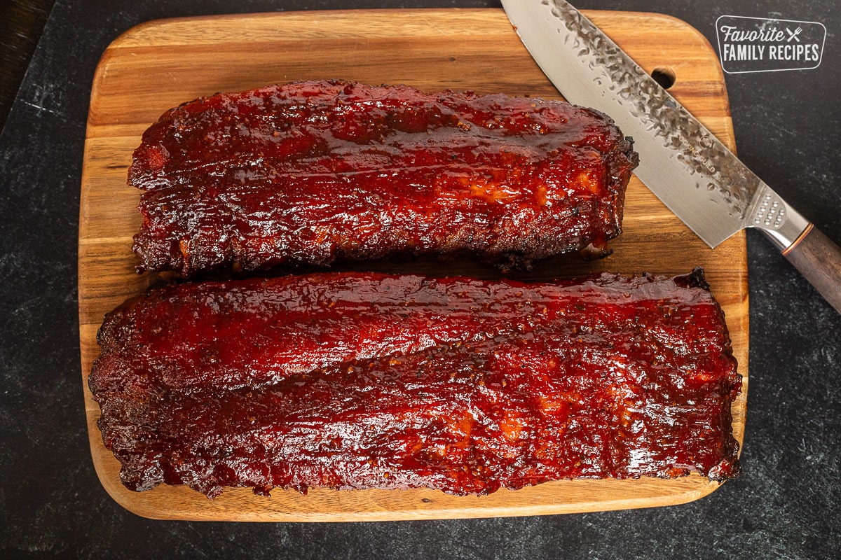 Cutting board with two racks of Easy Smoked Ribs and a knife.