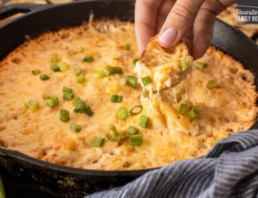 Dipping a slice of bread into a skillet of Hot Crab Dip.