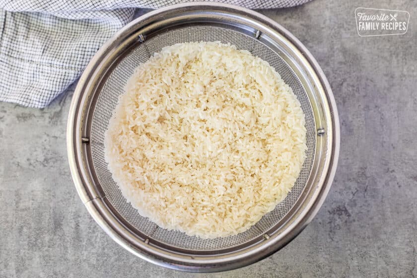 Metal colander with draining long grain rice.