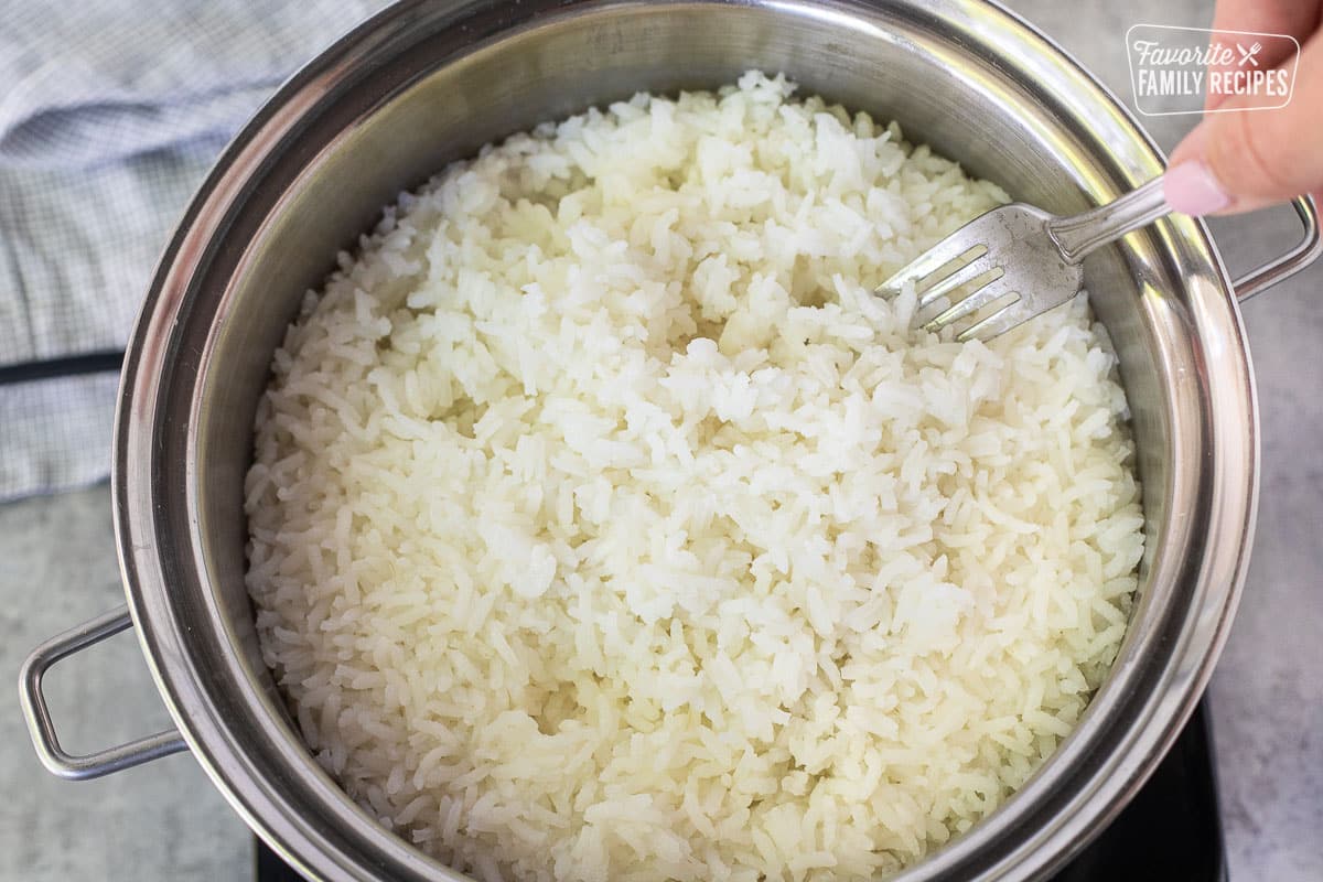 Fluffing up cooked long grain rice with a fork.