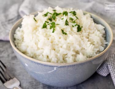 Bowl of Long Grain Rice topped with parsley for garnish.