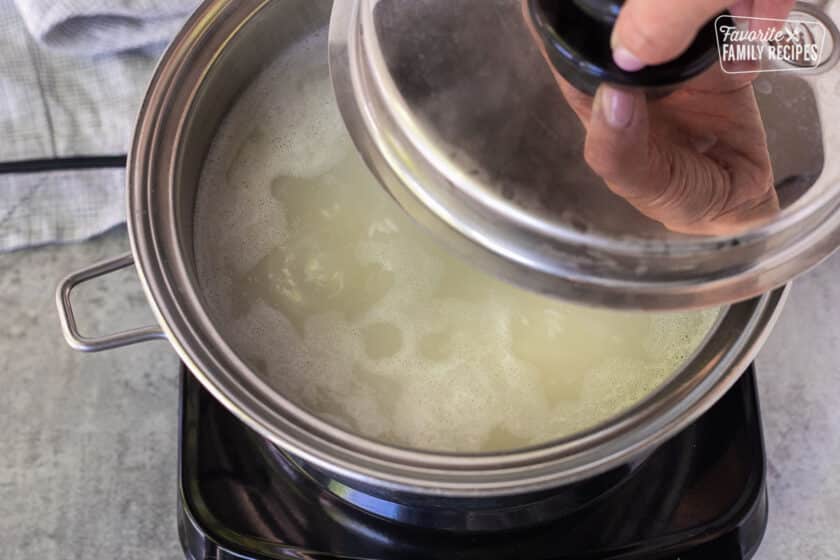 Placing lid on boiling pot of rice and water.