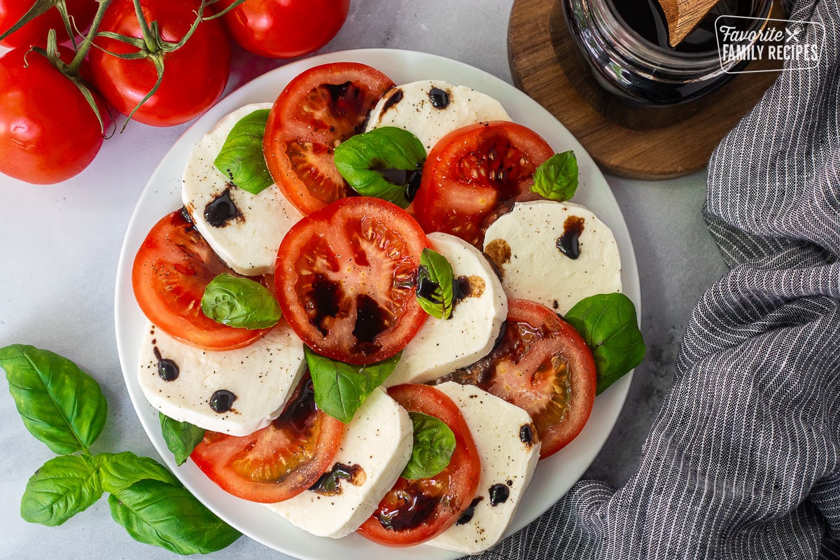 Balsamic glaze on top of caprese salad with tomatoes, basil and fresh mozzarella cheese.