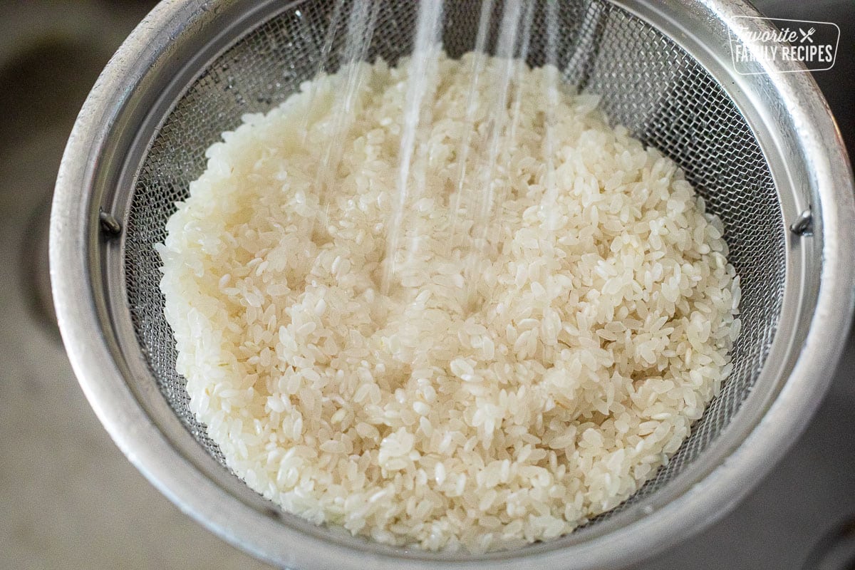 Rinsing rice in a colander in the sink.